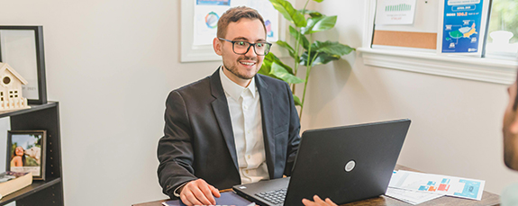 Smiling businessman working on a laptop at his desk