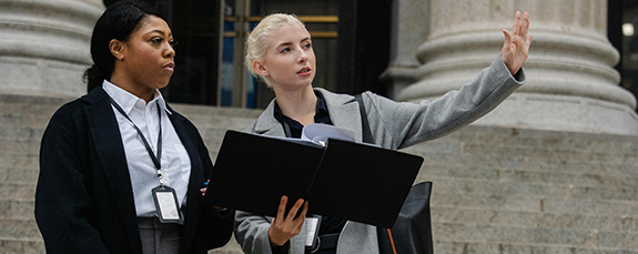 Two officials with a folder outside a government building