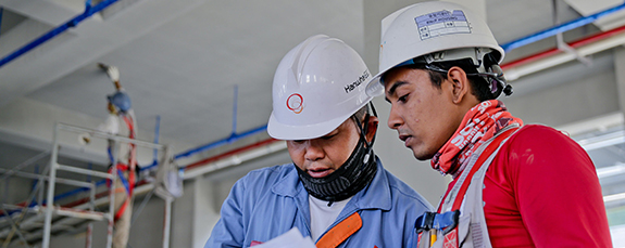 Engineers in hard hats reviewing plans on site