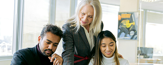 Manager helping two colleagues at a computer