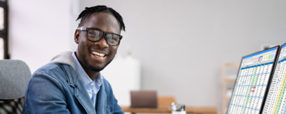 Smiling professional at a desk with financial charts on screen